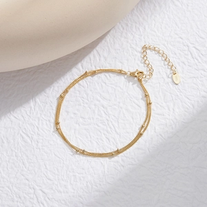 Macro detail of S925 sterling silver double-layer gold beaded bracelet on white background
