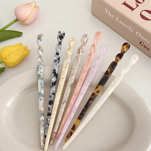 Minimalist acetate hair sticks with marble pattern in various colors on a ceramic tray