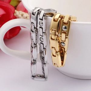 Macro view of magnetic health bracelets in silver and gold hanging on a ceramic cup