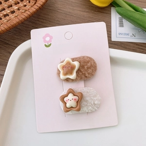 Detail of plush brown and beige star hair clips with smiley faces on display card