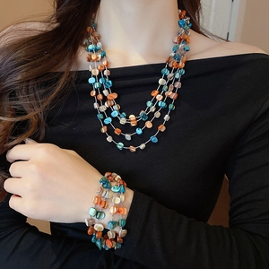 Detail showing multi-layer seashell bead necklace and bracelet set in blue and orange