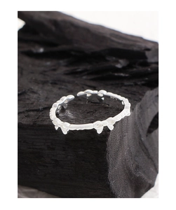 Macro shot of S925 sterling silver ring featuring continuous bow design on dark charcoal