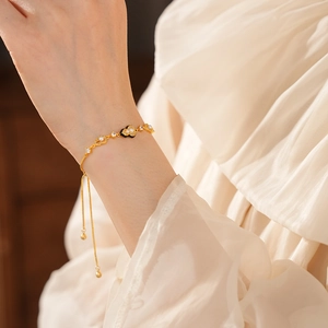 Detail of gold-plated bracelet with pearls and black heart charm on model wrist