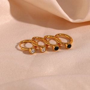 Macro shot of 18K gold-plated hoop earrings with clear and black cubic zirconia on pink satin
