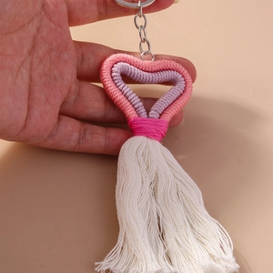 Detailed view of handmade pink knitted heart keychain with white tassels and metal ring
