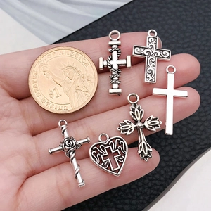 Maatvergelijking van zes zilveren kruishangers naast een munt voor doe-het-zelf sieraden