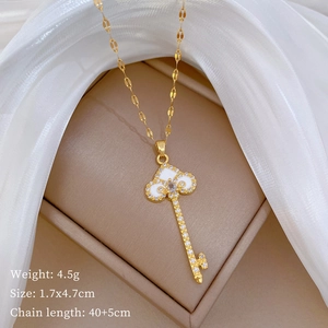 Detail of gold key pendant with sparkling crystals and white enamel on a jewelry pad