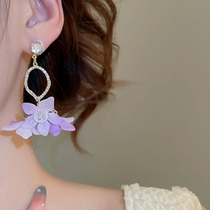 Detailed close-up of long floral drop earrings with purple petals and sparkling zircons