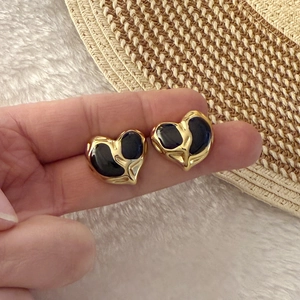 Minimalist gold heart-shaped earrings with black glossy enamel inlay in a stylish design