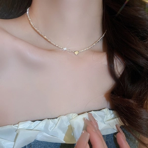 Close-up of minimalist silver beaded necklace featuring a small heart pendant on a model