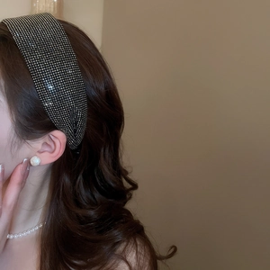 Macro detail of wide black headband with pavé-set silver rhinestones on model's hair