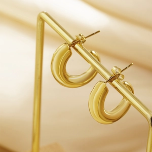 Detail of polished gold chunky U-shaped earrings on a metal display stand