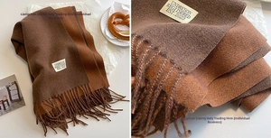 Detail view of a soft brown cashmere-feel scarf with fringe and vintage-style props