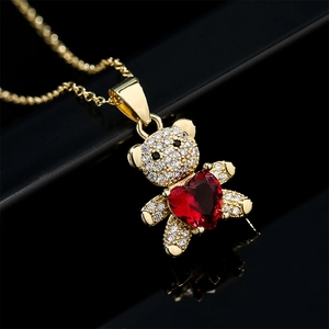 Collier ours en peluche doré avec zircons et pierre en cœur rouge sur fond noir
