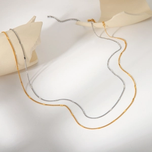 Minimalist gold and silver stainless steel cable chain necklaces on ceramic decor