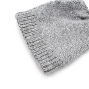 Gros plan du bonnet en fourrure de lapin gris clair montrant la texture tricotée