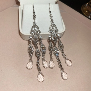 Detail of silver drop earrings with crystal clusters and teardrop pendant on white box