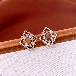Detail of hollow diamond-shaped earrings with tiger eye stone in retro silver finish