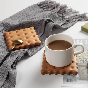 Minimalist walnut wood biscuit-shaped coffee coaster set on a grey knit fabric background