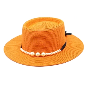 Vista dettagliata di un cappello di paglia arancione con nastro nero e decori di perle