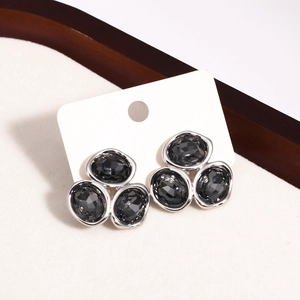 Dettaglio di orecchini a lobo geometrici con zirconi grigio scuro e montatura argento