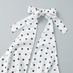 Close-up of white polka dot fabric with an elegant self-tie bow on the neckline