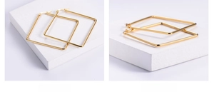 Detailed macro view of square gold titanium earrings with polished mirror finish