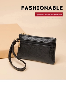 Detail of black pebbled leather mini wallet with gold double zippers and wrist strap