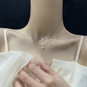 Double-layered silver necklace featuring cross pendant and sparkling zircon water drop charms