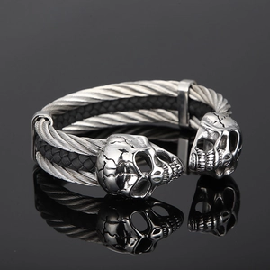 Macro shot of punk style skull head open bracelet with black woven leather cord detail