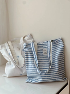 Detailed embroidery of blue bows on white and striped canvas tote bags for daily use