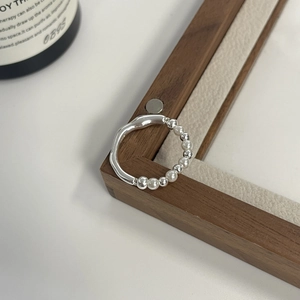 Detail shot of S925 sterling silver wavy band with white beads on dark wood frame