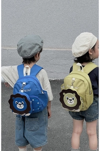 Kids backpack showing blue and yellow-green lion designs worn by models on plain wall