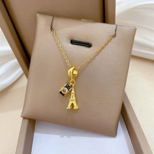Detailed close-up of a gold camera and Eiffel Tower pendant necklace on champagne satin