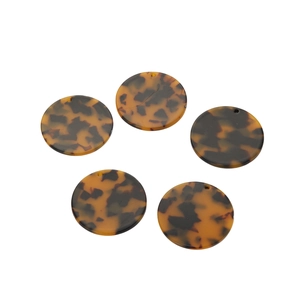 Five pieces of leopard print acrylic round charms for DIY jewelry making on white background