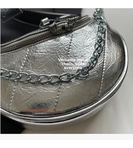 Detail of silver metallic dumpling bag with quilted texture and chunky metal chain strap