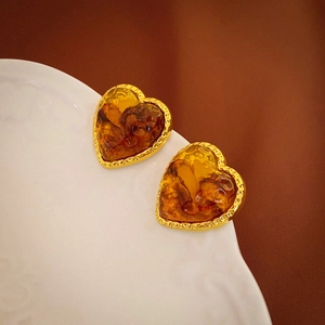 Detailed macro view of heart-shaped amber resin earrings with textured gold metal borders