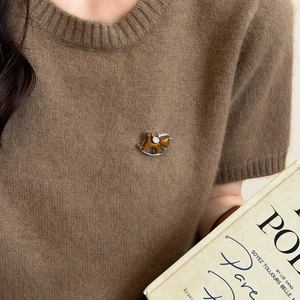 Detail einer braunen Schaukelpferd-Brosche mit Strass auf einem Strickpullover