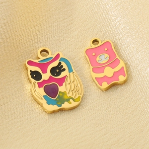 Close-up of gold stainless steel owl and bear charms with colorful enamel details