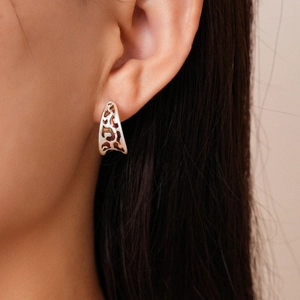 Close-up of C-shaped metallic earring with leopard print oil drop finish worn by model