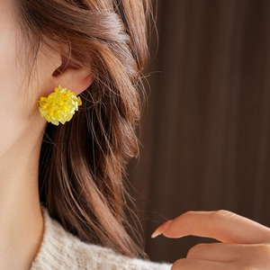 Close-up of yellow crystal bead flower cluster earrings worn by a female model