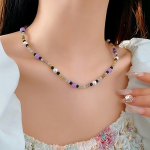 Detail of colorful pearl and gemstone choker necklace on model with floral shirt
