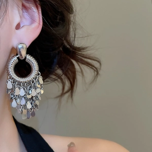 Detail of silver geometric fringe tassel earrings showing metallic texture on model ear