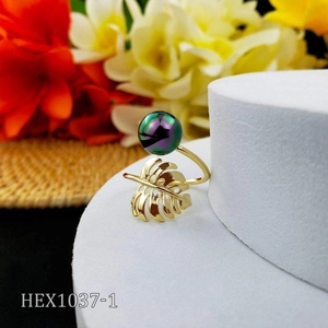 Detail of gold monstera leaf ring featuring a purple iridescent pearl on white pedestal