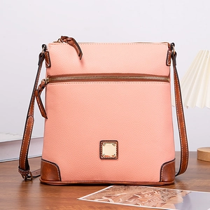 Close-up of pink lychee textured leather crossbody bag with brown trim and gold metal logo