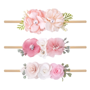 Detailed view of three floral baby headbands with pearls, rhinestones and nylon bands