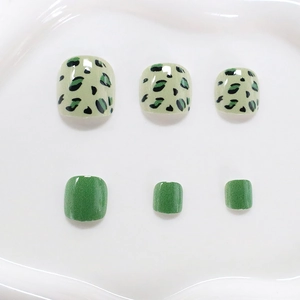 Short green press-on toenails featuring leopard print patterns and solid green finish