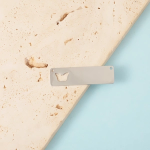 Detailed view of silver rectangular stainless steel charm with butterfly cutout and dual holes