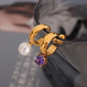 Golden huggie earrings with pearl and purple zircon pendants on glass rim