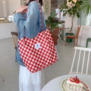 Detail of red and white checkered canvas tote bag with metal snap button closure
